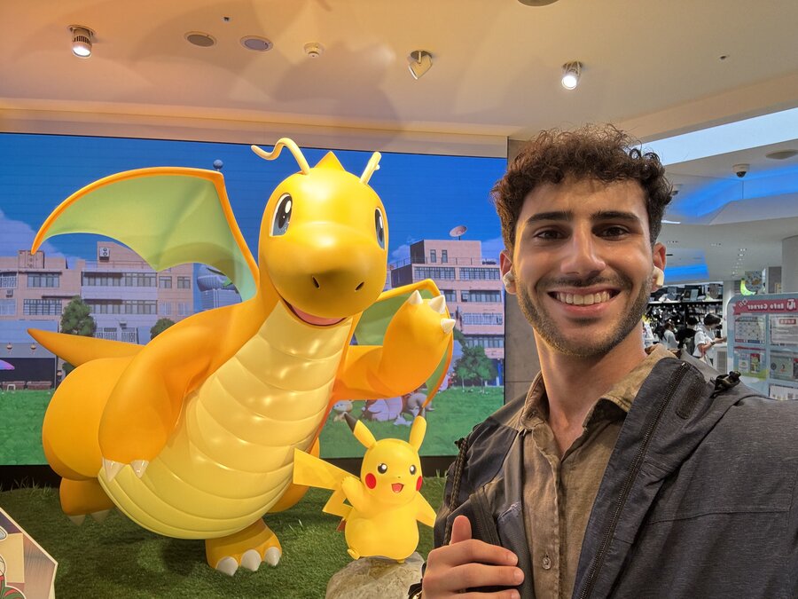Joseph grinning in front of a giant Dragonite and Pikachu display